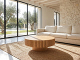 Udine Natural Wood Veneer Fluted Pedestal Coffee Table on a jute rug in front of a linen sofa in a poolside villa