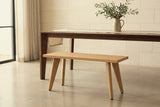 Umbertide light oak bench along a dark walnut dining table in an Austin dining room with a pale limestone wall and a polished concrete floor (table not included)