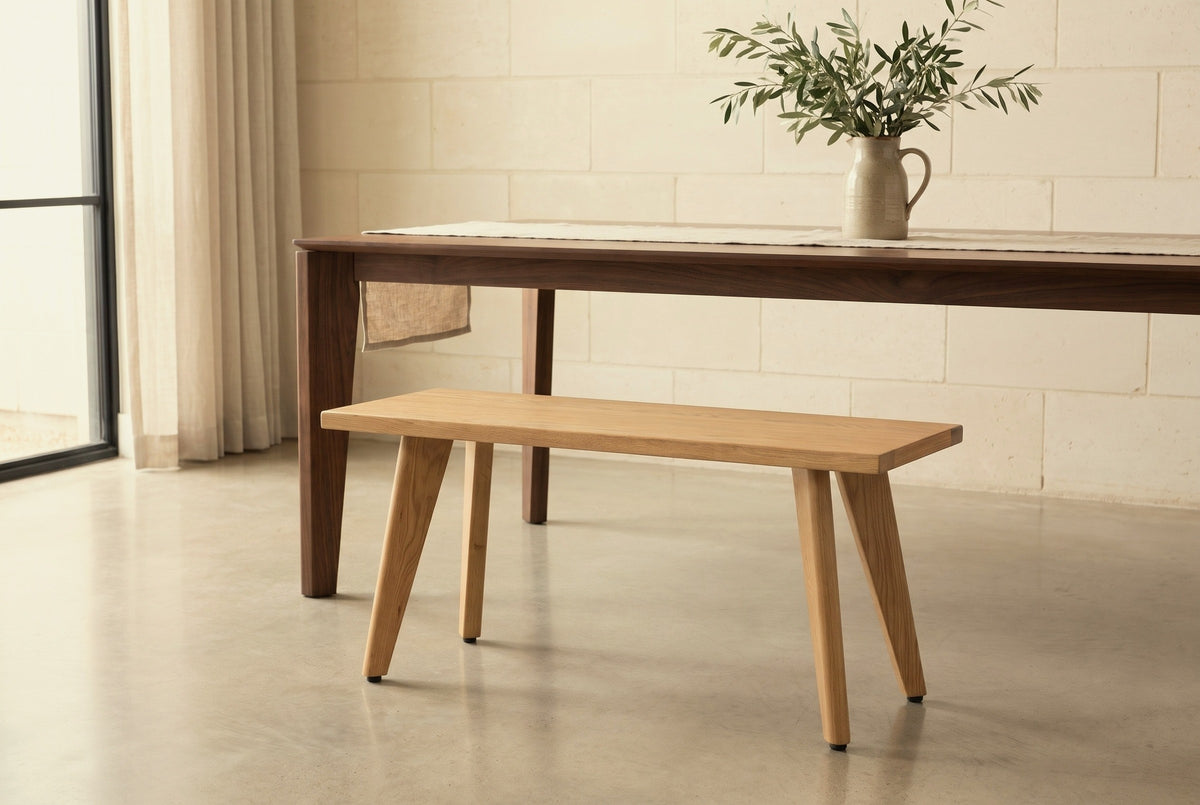 Umbertide light oak bench along a dark walnut dining table in an Austin dining room with a pale limestone wall and a polished concrete floor (table not included)