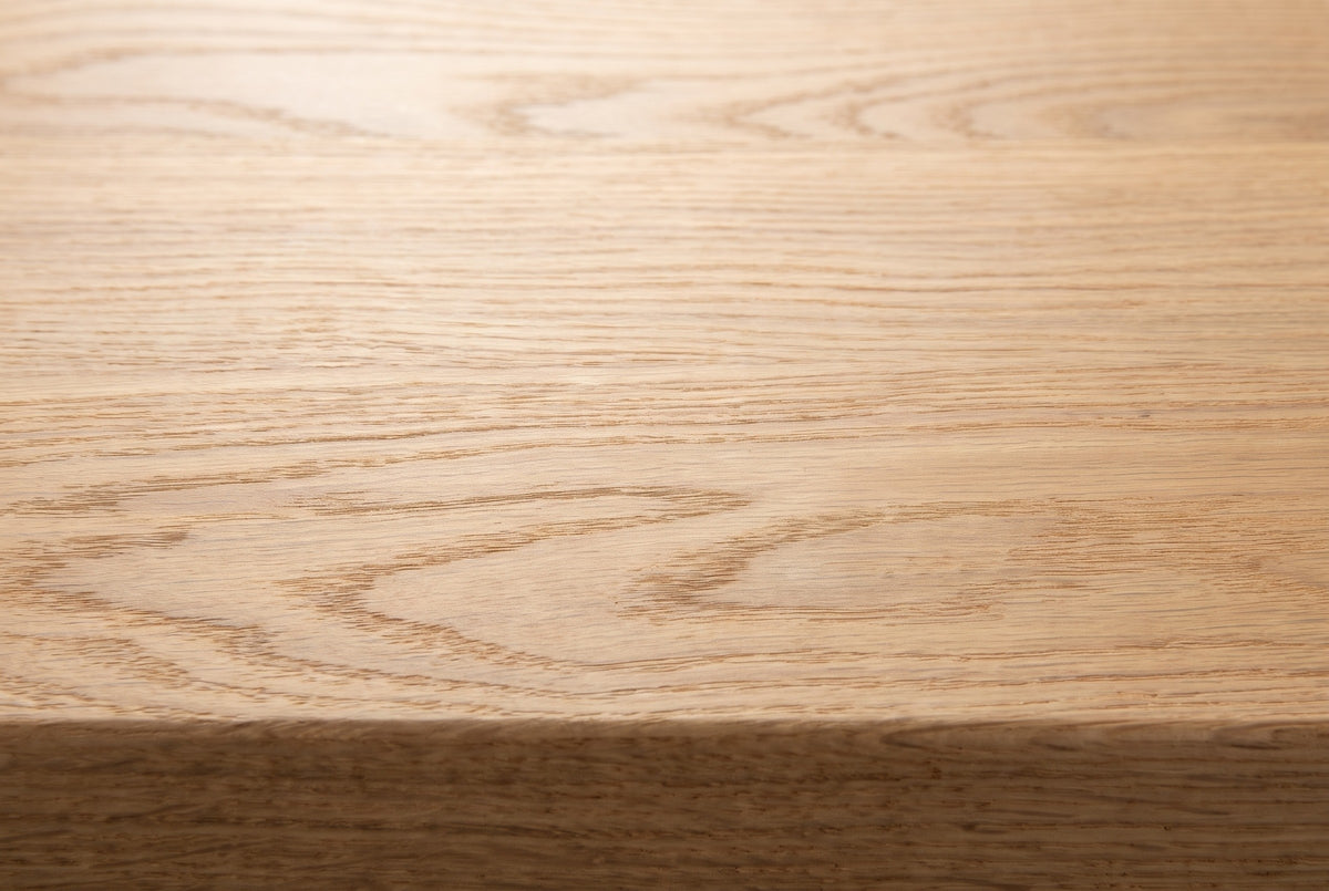 Close-up of the solid red oak on the Umbertide bench: light honey-beige open grain running to the eased edge of the top