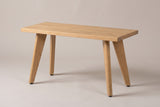The Umbertide bench in natural red oak, three-quarter view on a light studio backdrop