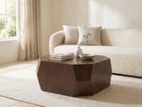 Urbino Acacia Veneer Faceted Coffee Table styled with books, a vase and a stone bowl in front of a cream sofa in a bright plaster room