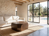 Urbino Acacia Veneer Faceted Coffee Table on a jute rug in front of a linen sofa in a poolside villa