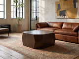 Urbino Acacia Veneer Faceted Coffee Table on a vintage rug in front of a leather sofa in an industrial loft