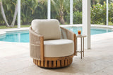 Ustica swivel lounge chair on a covered pool lanai in Naples, Florida, cream travertine pavers, a turquoise pool and palms behind (side table not included)