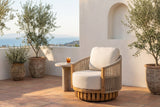 Ustica swivel lounge chair on a terracotta-tiled terrace in Southern California at golden hour, a white plaster wall with an arched niche and olive trees behind (side table not included)