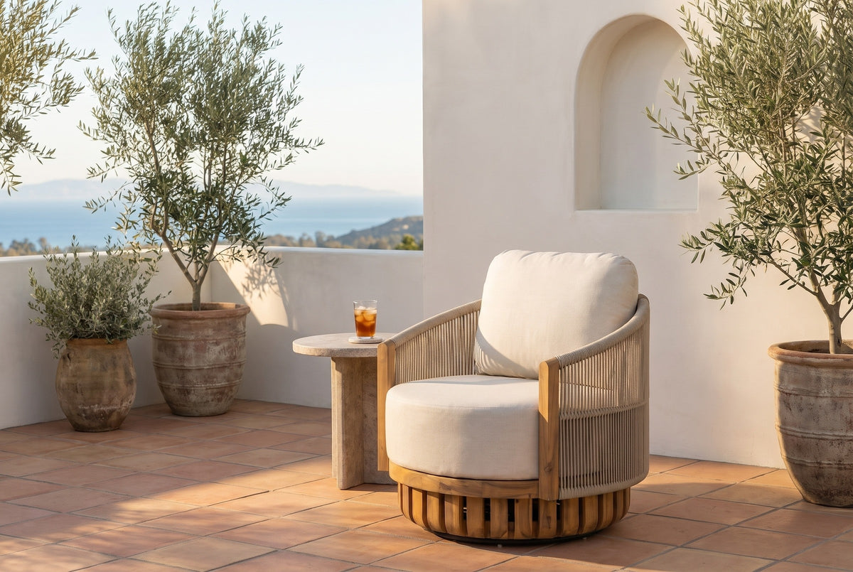 Ustica swivel lounge chair on a terracotta-tiled terrace in Southern California at golden hour, a white plaster wall with an arched niche and olive trees behind (side table not included)