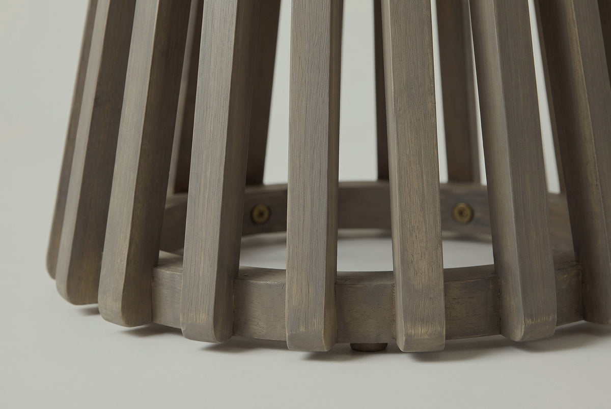 Close-up of the acacia on the Valderice side table: slat ends and the floor ring in a weathered grey finish with the grain showing