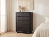 Valdobbiadene 40-Inch Burnished Black 5-Drawer Chest against a plaster wall under an abstract canvas in a bright bedroom
