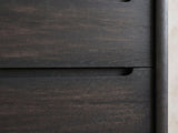 Close-up of the Valdobbiadene 40-Inch Burnished Black 5-Drawer Chest: the carved finger channel and the rounded corner post in burnished black ash