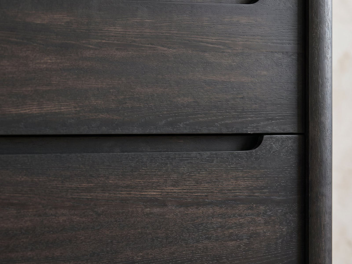 Close-up of the Valdobbiadene 40-Inch Burnished Black 5-Drawer Chest: the carved finger channel and the rounded corner post in burnished black ash