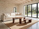 Valenza 50-Inch Freeform Walnut-Stained Veneer Nesting Coffee Tables, Set of 2 on a jute rug in front of a linen sofa in a poolside villa
