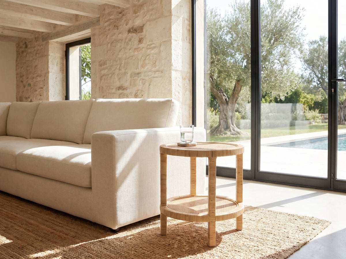 Valsinni Rattan Round Two-Tier Side Table beside a linen sofa in a poolside villa