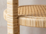Close-up of the Valsinni Rattan Round Two-Tier Side Table: a rattan-wrapped leg passing through the rim of the lower shelf