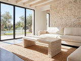 Varallo Reclaimed Pine Waterfall Coffee Table on a jute rug in front of a linen sofa in a poolside villa