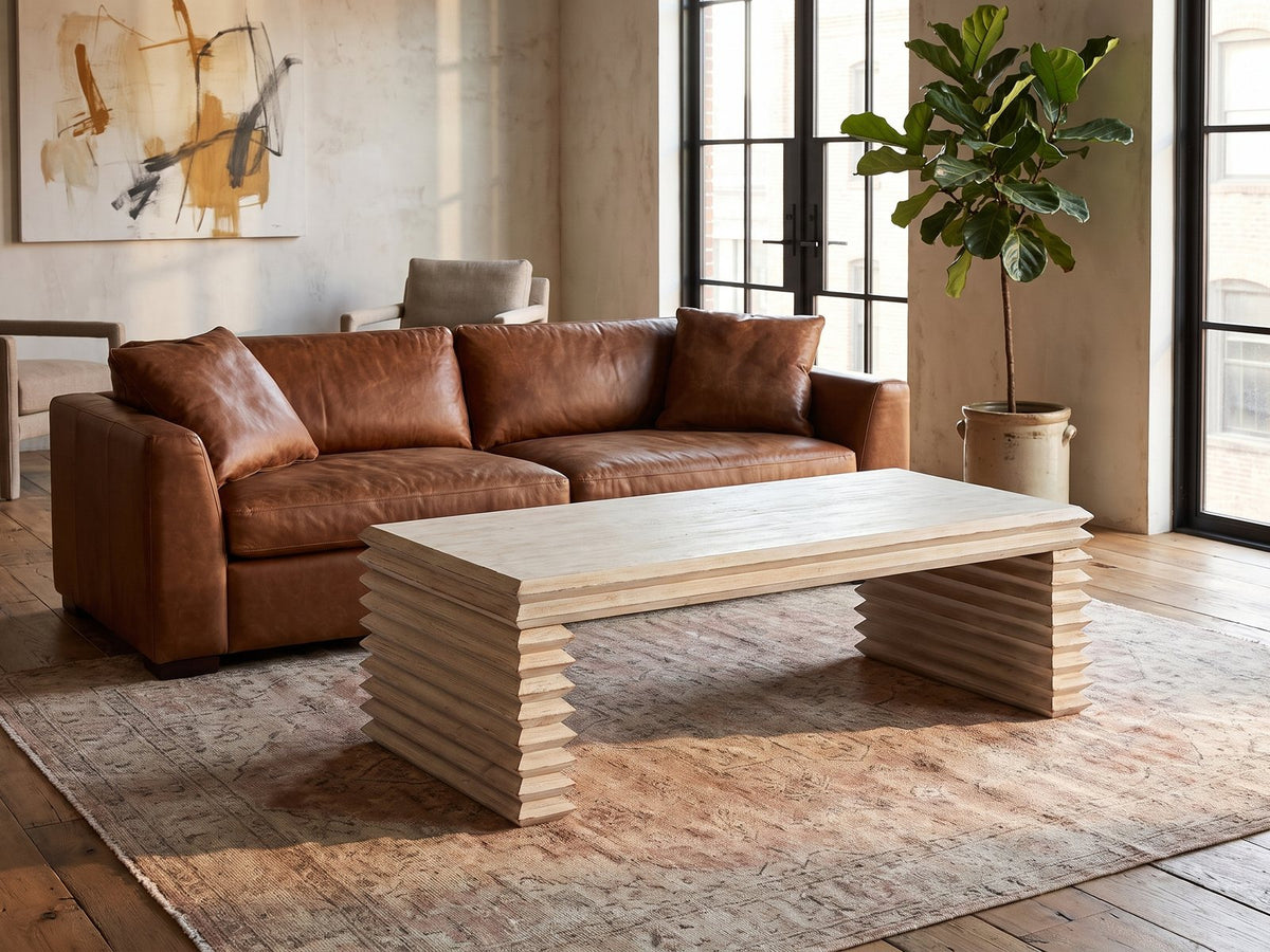 Varallo Reclaimed Pine Waterfall Coffee Table on a vintage rug in front of a leather sofa in an industrial loft