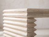 Close-up of the Varallo Reclaimed Pine Waterfall Coffee Table: the stacked, chevron-edged pine boards of one leg under the top