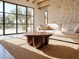 Bolgheri Sculpted Mango Coffee Table on a jute rug in front of a linen sofa in a poolside villa