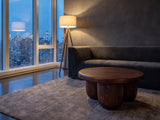 Bolgheri Sculpted Mango Coffee Table on a wool rug in front of a velvet sofa in a city penthouse at blue hour