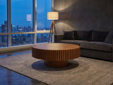 Vernazza Wood Veneer Fluted Pedestal Coffee Table on a wool rug in front of a velvet sofa in a city penthouse at blue hour