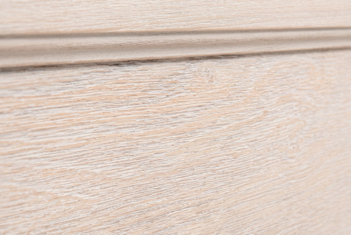 Close-up of the pale washed oak on the Villacidro nightstand: open pores showing as fine white lines beside a stepped moulding