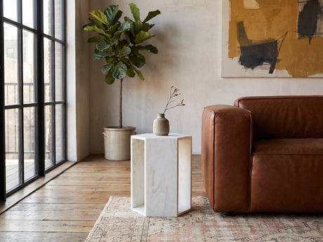 Vitozza White Marble Hexagon Side Table beside a leather sofa in an industrial loft