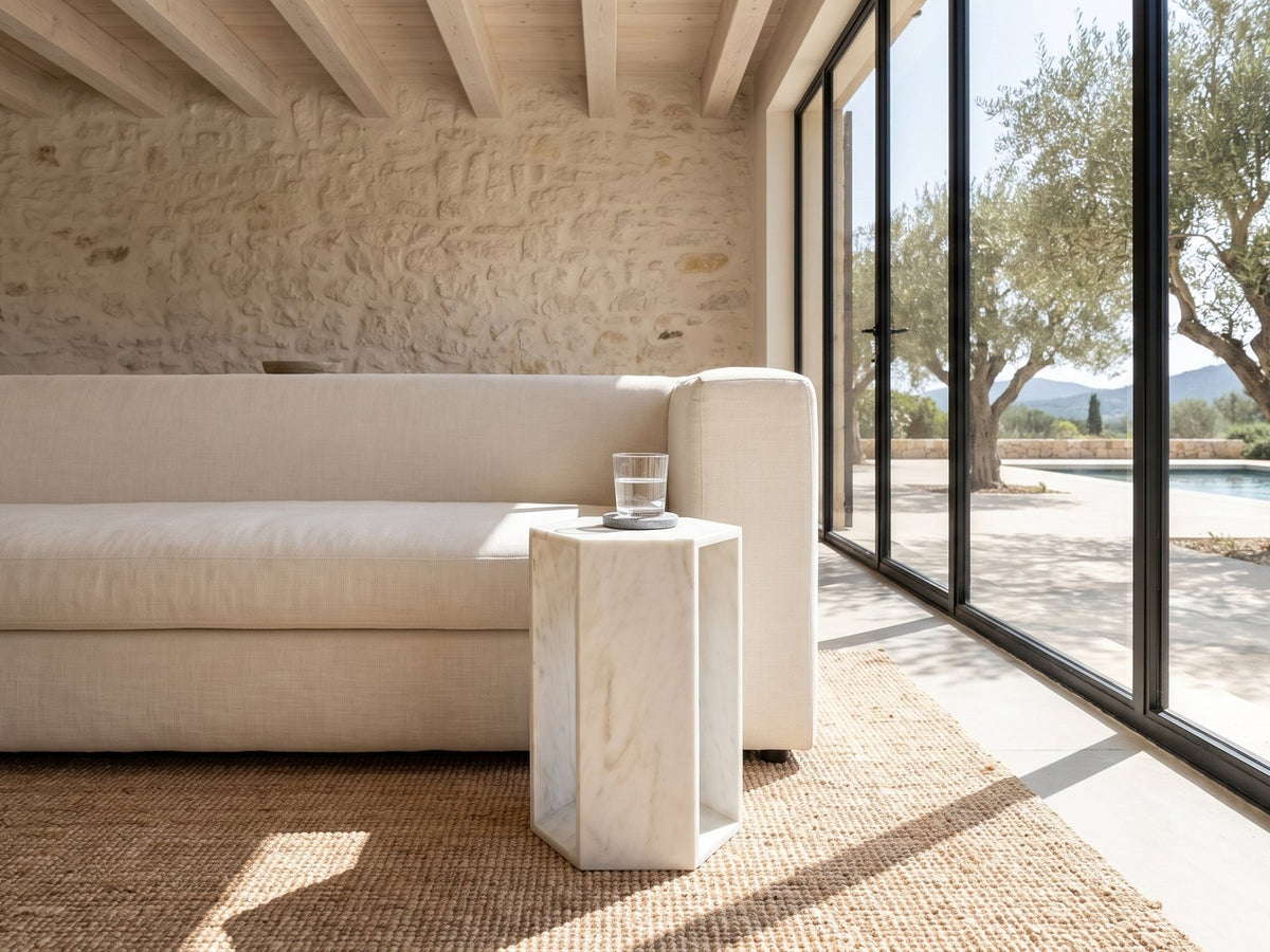 Vitozza White Marble Hexagon Side Table beside a linen sofa in a poolside villa