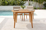 Vittoria round acacia dining table on a travertine pool terrace in Naples, Florida, a white coquina wall, sea grape and palms behind (chairs and tableware not included)
