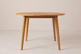 The Vittoria round dining table seen straight from the front: the thin slatted top on four splayed tapered legs