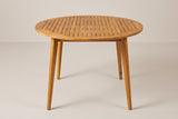 The Vittoria round acacia dining table in teak finish on a light studio backdrop (sold without chairs)