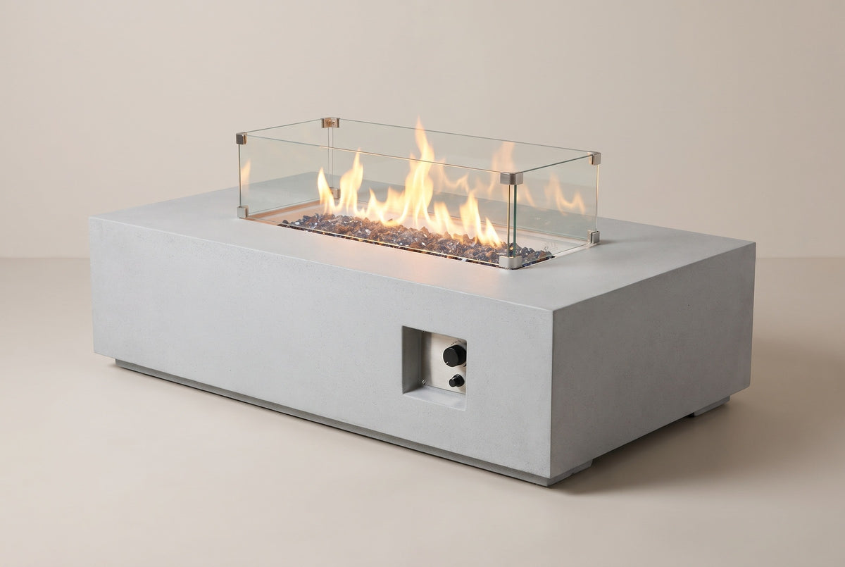 The Vulcano concrete fire pit table with a lit flame, three-quarter view from the front on a light studio backdrop
