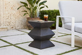 Zafferana geometric side table on concrete pavers with grass joints in a Coral Gables garden, a coral-stone wall and a bird of paradise, beside a white aluminium lounge chair (chair, glass and almonds not included)