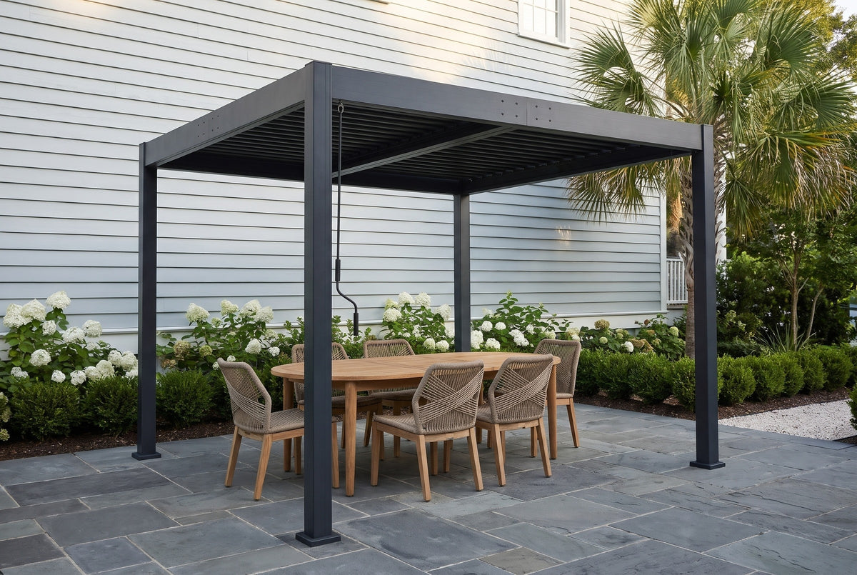 Zingaro black louvered pergola over a bluestone patio beside a grey-blue clapboard house in Beaufort, South Carolina, with white hydrangeas and a palmetto (furniture not included)