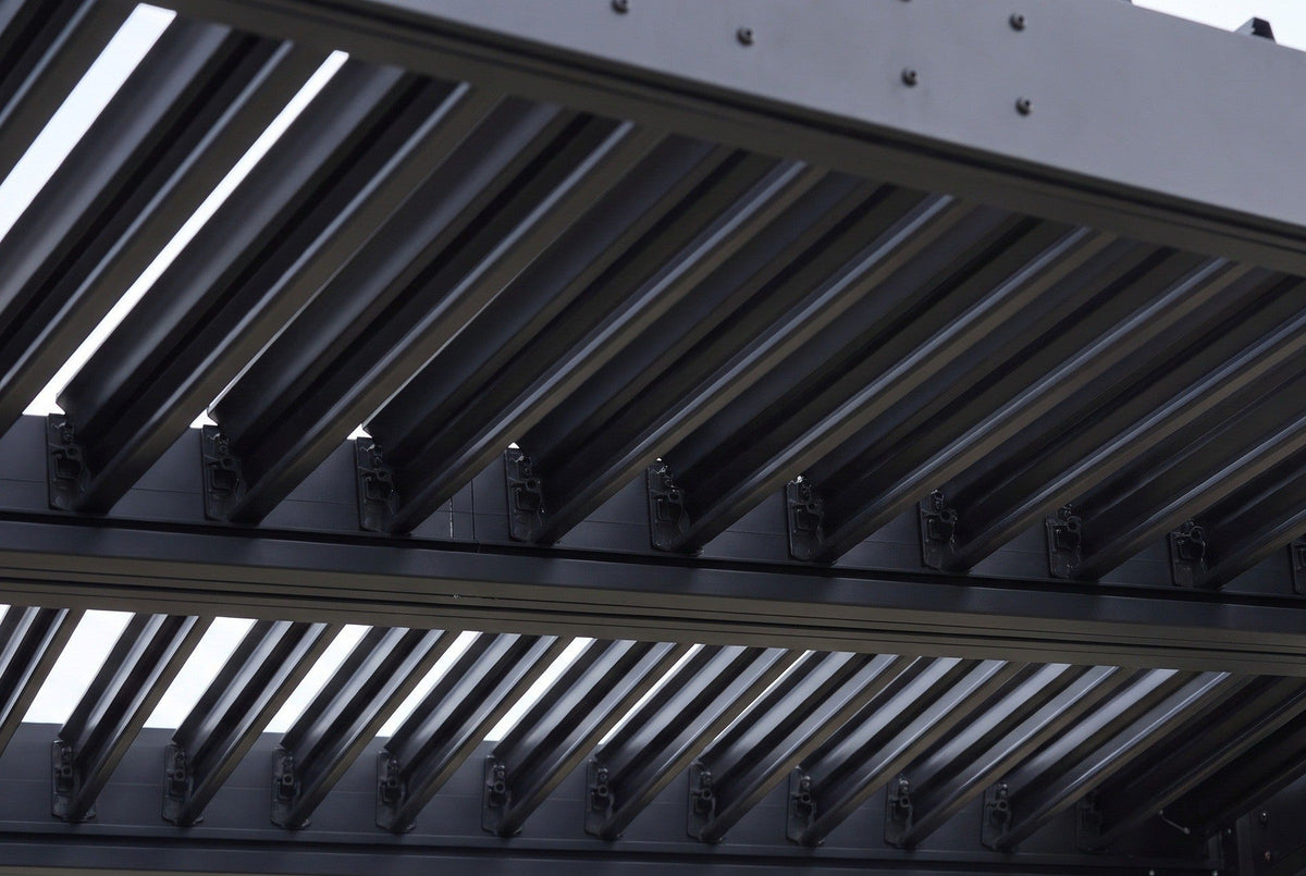Close-up of the louver blades of the Zingaro pergola in matte black, seated on pivot caps along the beams