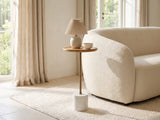 Zollino Mango and Marble Pedestal Side Table with a lamp and a ceramic bowl beside a cream boucle armchair in a bright plaster room