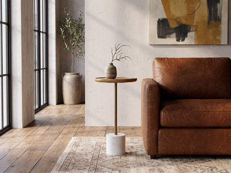 Zollino Mango and Marble Pedestal Side Table beside a cognac leather armchair in an industrial loft