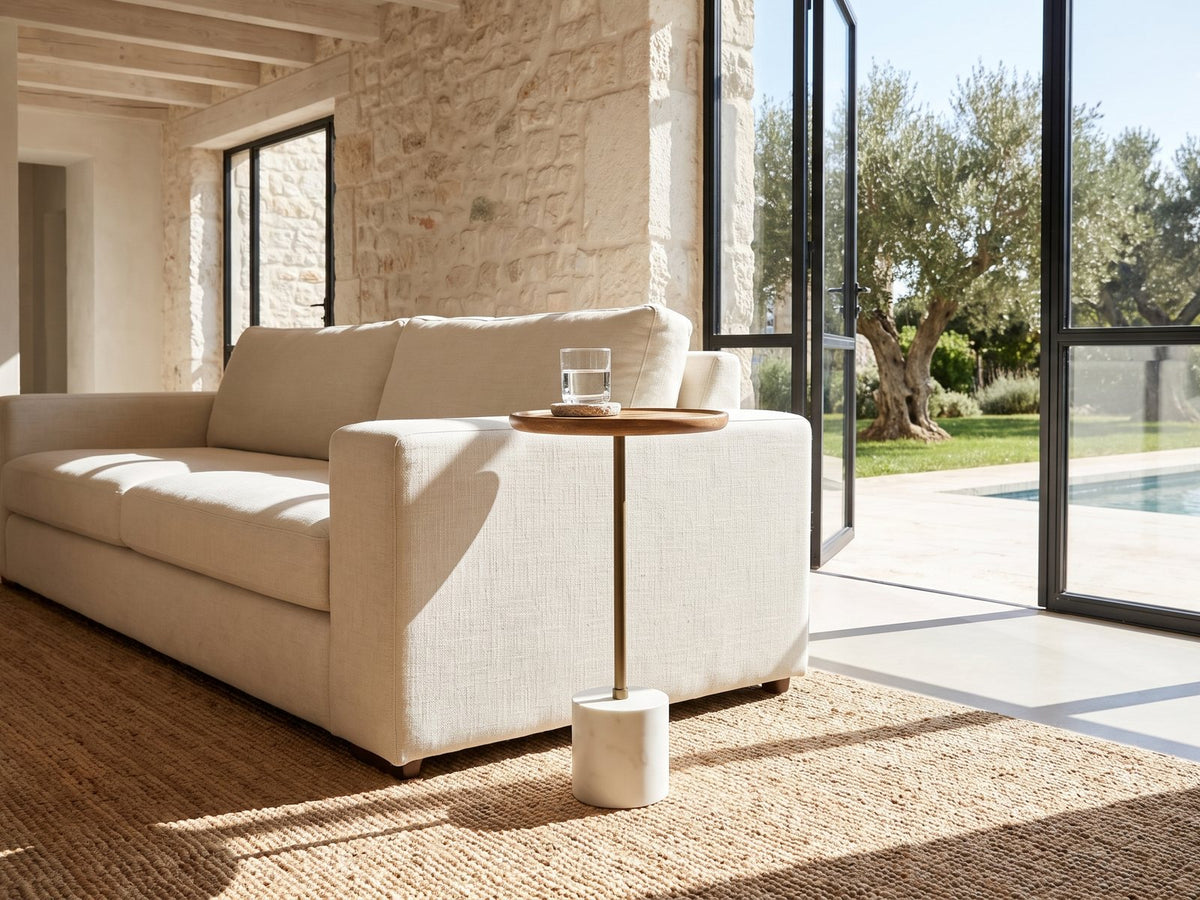 Zollino Mango and Marble Pedestal Side Table beside a linen sofa in a poolside villa